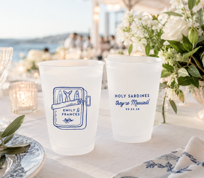 Wedding reception frosted cups with personalized Sardine design on a table with flowers and candles.