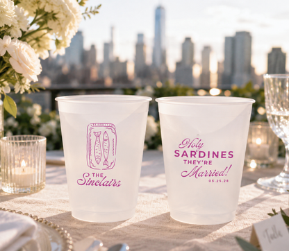 wedding coastal city Frosted cups with pink text on a table outdoors with a city skyline in the background.