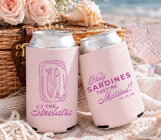Two pink can coolers with personalized Sardine inspired design text on a beach setting with flowers and a basket.