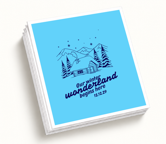 Personalized blue Our Winter Wonderland wedding napkins featuring snowy mountain cabin illustration, pine trees, navy artwork, and wedding date.