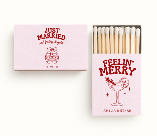 Personalized blush pink Christmas wedding matchboxes featuring red holiday cocktail artwork, Christmas ornament illustration, couple names, and wedding date.