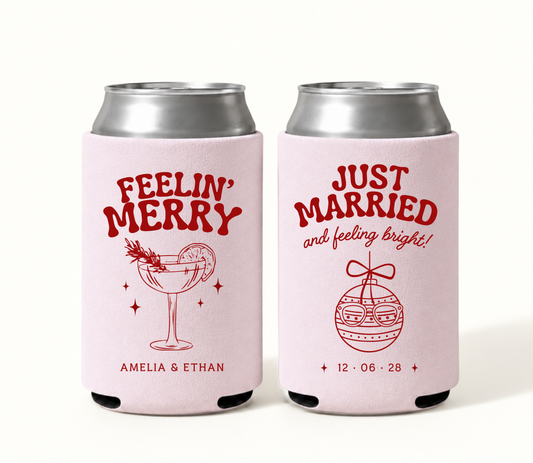 Personalized blush pink Feelin’ Merry Christmas wedding can coolers featuring red holiday cocktail artwork, Amelia and Ethan names, Just Married ornament, and wedding date 12.06.28.