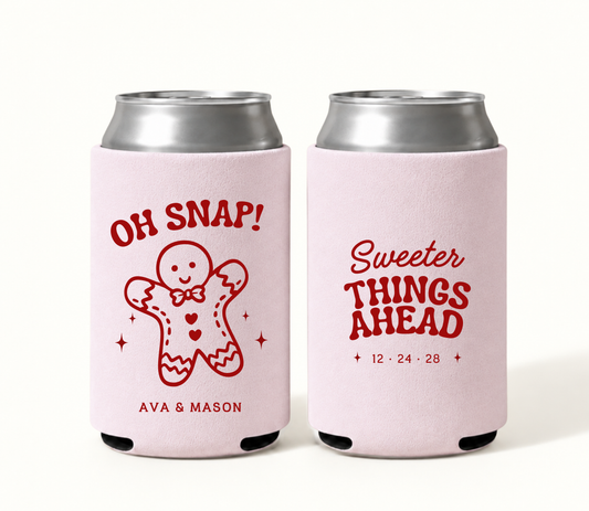 Personalized blush pink Oh Snap gingerbread Christmas wedding can coolers featuring red broken gingerbread cookie artwork, Ava and Mason names, Sweeter Things Ahead wording, and wedding date 12.24.28.