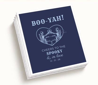 Personalized Boo-Yah navy Halloween wedding cocktail napkins featuring a skeleton bride and groom toasting inside a heart with custom wedding date.