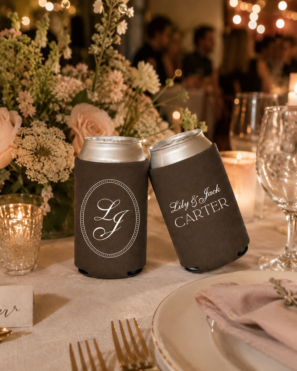 wedding can coolers with monogrammed designs on a table setting with flowers and candles.