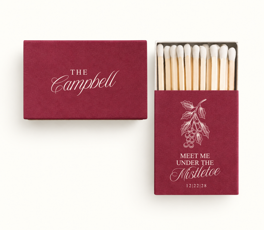 Personalized burgundy Meet Me Under The Mistletoe wedding matchboxes featuring ivory mistletoe artwork, Campbell name design, and wedding date.