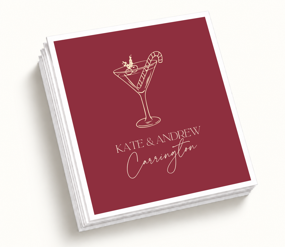 Personalized Christmas cocktail wedding napkins featuring burgundy background, ivory holiday cocktail illustration, candy cane detail, and custom wedding names.
