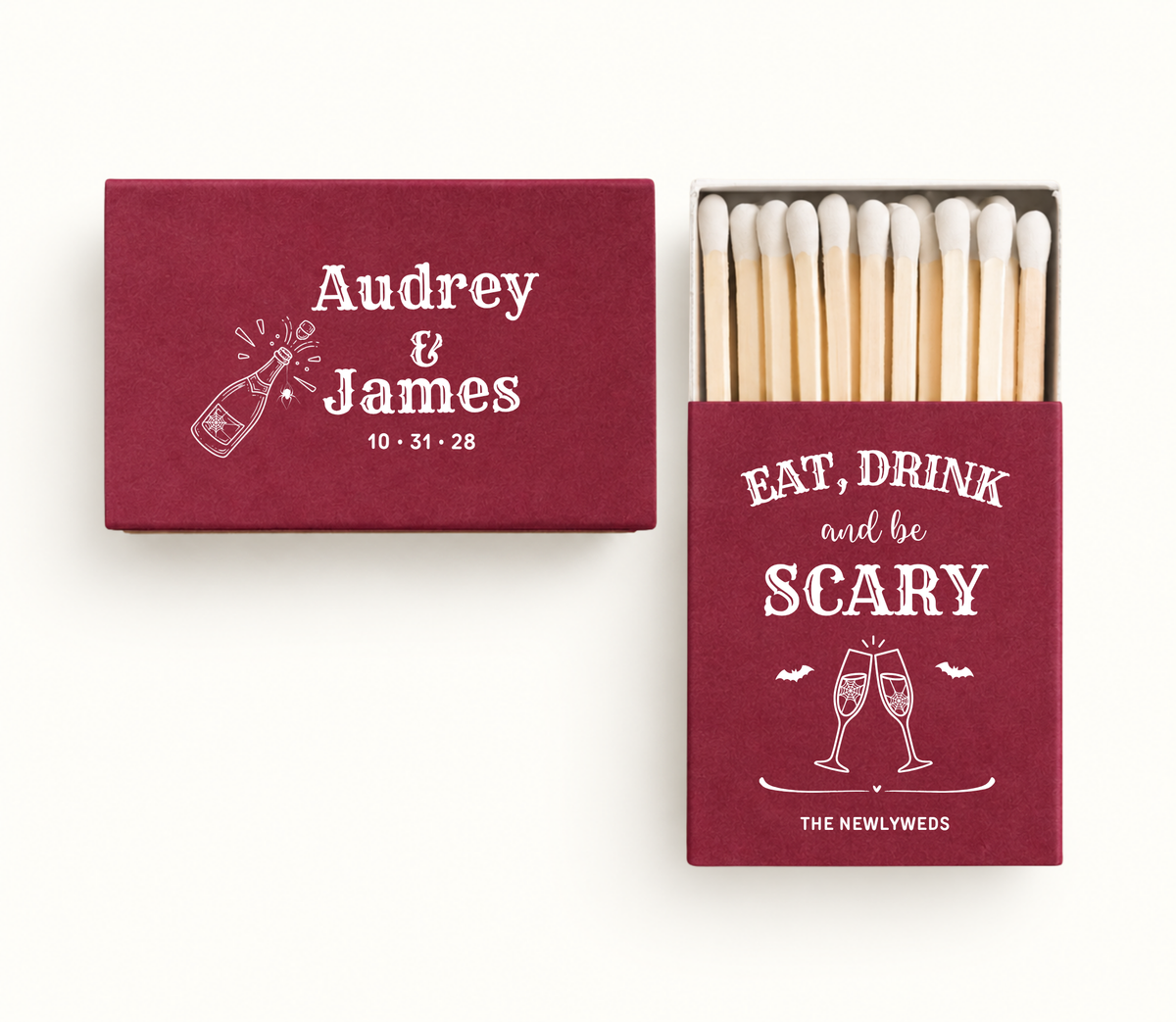 Personalized burgundy Eat Drink and Be Scary wedding matchboxes featuring white champagne glasses, bats, Audrey and James names, and custom wedding date 10.31.28.