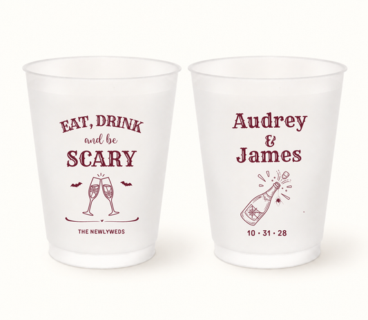 Personalized burgundy Eat Drink and Be Scary Halloween frosted wedding cups featuring champagne glasses, bats, Audrey and James names, champagne bottle, and wedding date 10.31.28.
