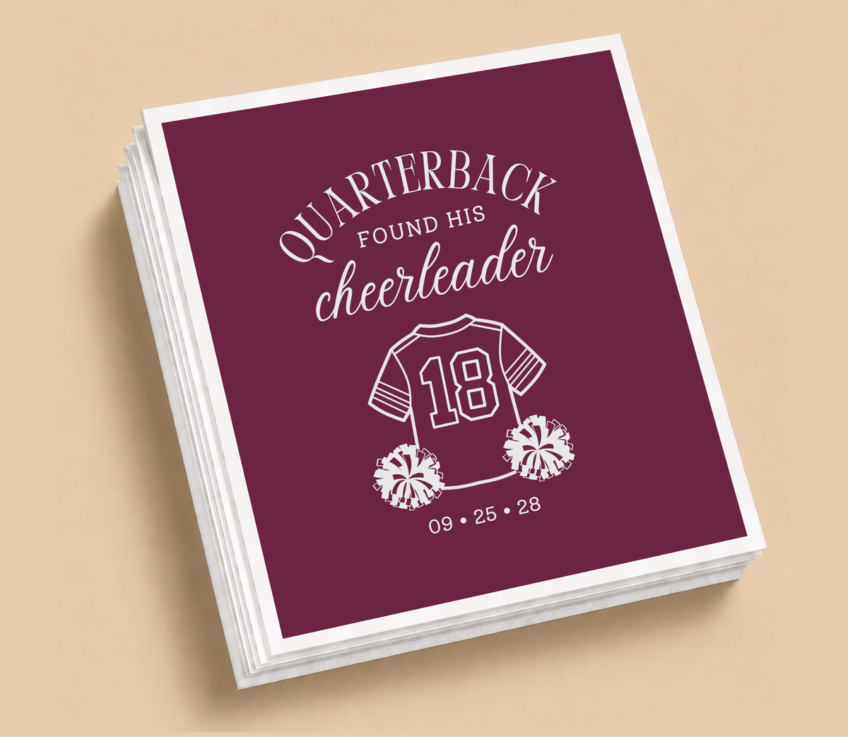 Personalized Quarterback Cheerleader football wedding napkin featuring burgundy background, football jersey with pom poms, romantic lettering, and wedding date.
