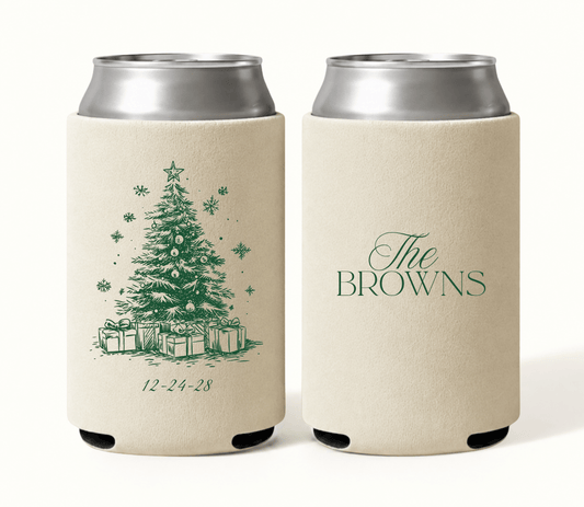 Personalized cream Christmas wedding can coolers featuring green Christmas tree artwork, snowflakes, ornaments, wrapped presents, custom family name, and wedding date.

