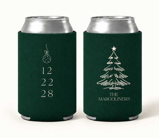 Personalized emerald green Christmas wedding can coolers featuring ivory Christmas tree artwork, hanging ornament, custom family name, and wedding date.