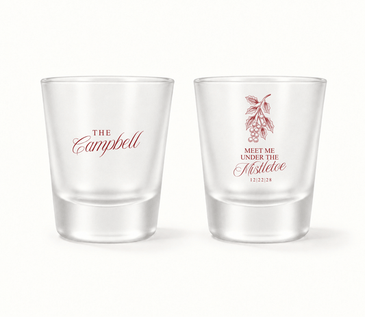 Personalized Meet Me Under The Mistletoe Christmas wedding shot glasses featuring mistletoe artwork, custom family name, and wedding date.