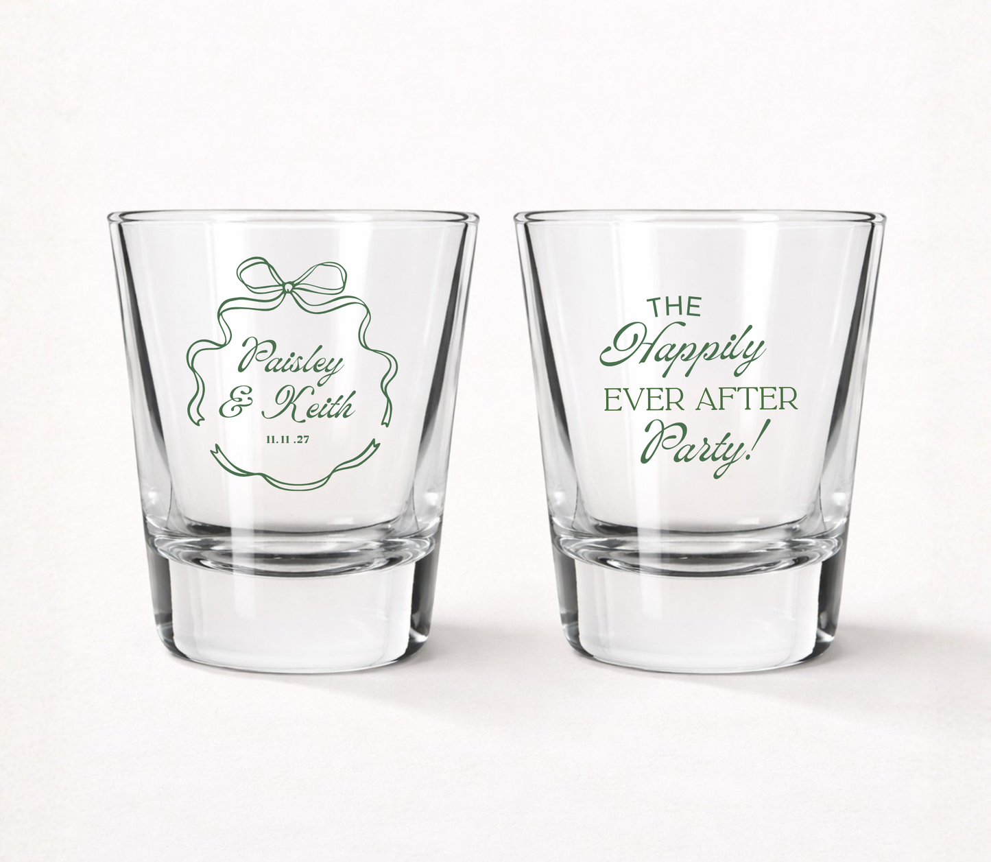 Clear personalized elegant wedding shot glasses featuring custom couple names, ribbon frame artwork, Happily Ever After Party design, and wedding date.