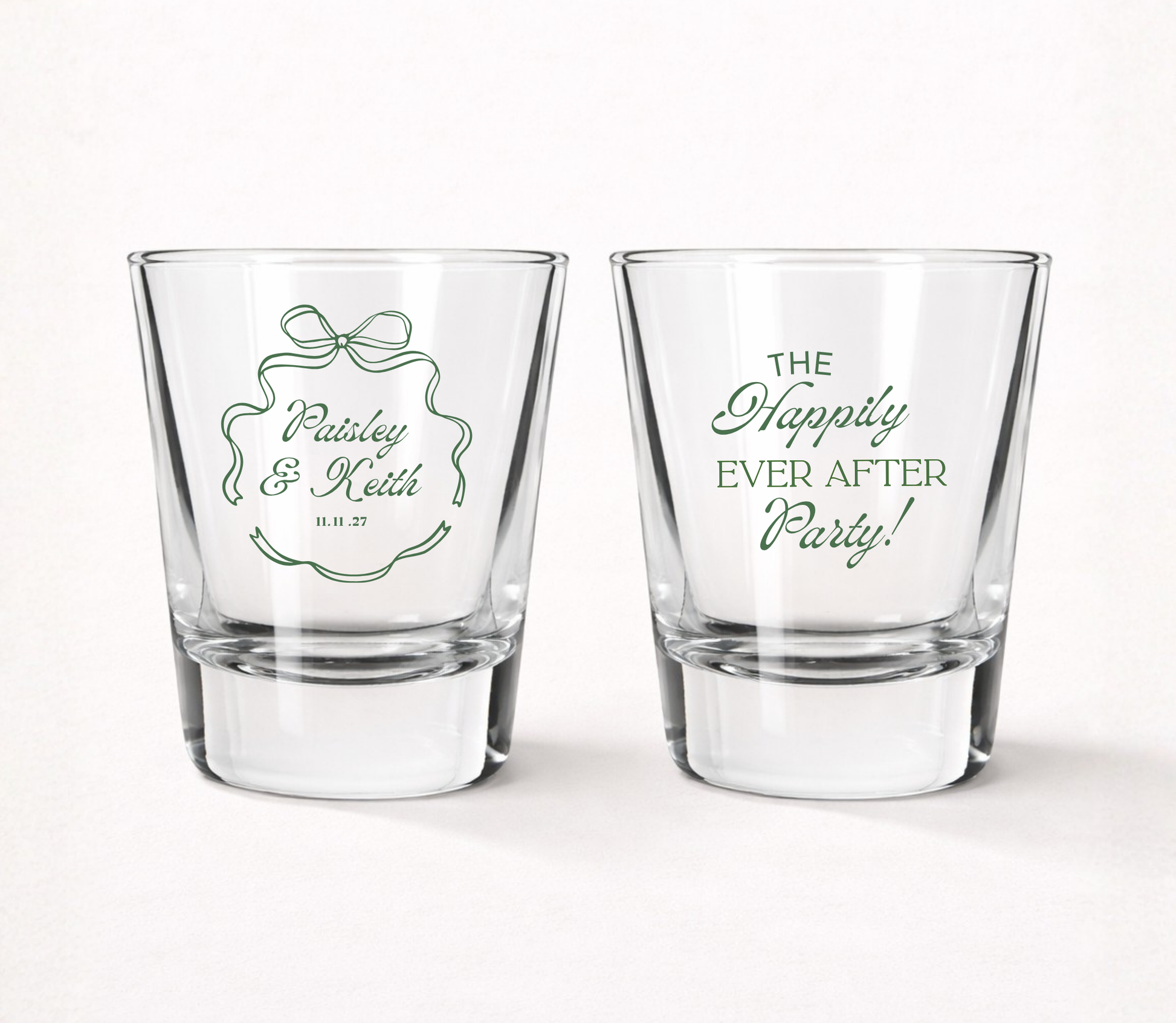 Clear personalized elegant wedding shot glasses featuring custom couple names, ribbon frame artwork, Happily Ever After Party design, and wedding date.