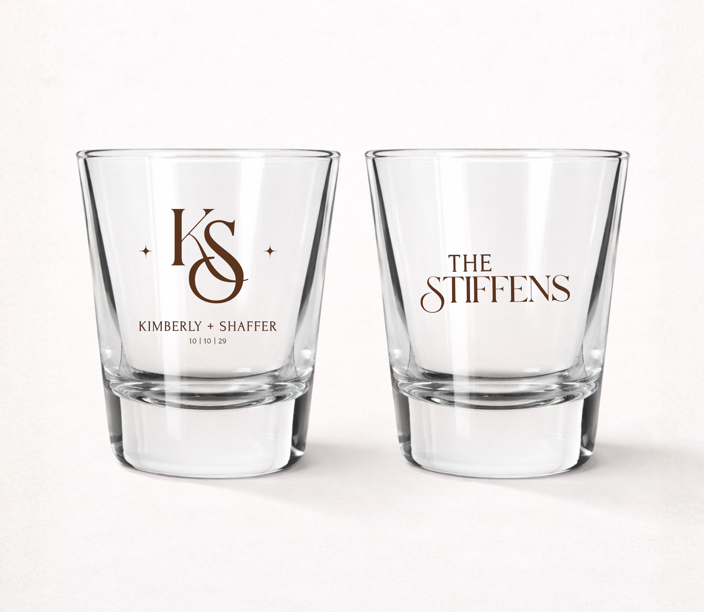 Clear personalized monogram wedding shot glasses featuring elegant custom initials, couple names, family surname, and wedding date.