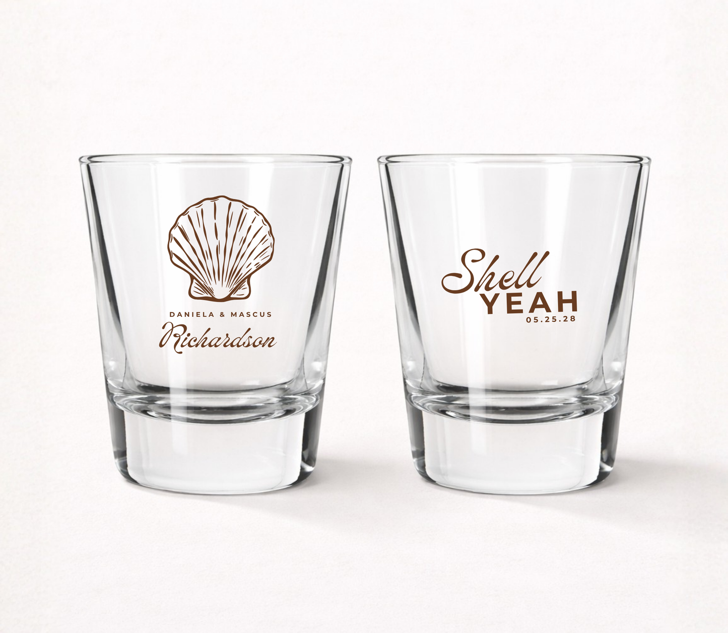 Clear personalized wedding shot glasses featuring a coastal seashell design, couple names, wedding date, and Shell Yeah wedding artwork.