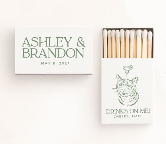 White personalized cocktail cat wedding matchboxes featuring a custom cat illustration with a cocktail glass, elegant green serif typography, couple names, wedding date, and premium safety matches.
Personalized cocktail cat wedding matchbox featuring a custom cat illustration and elegant serif typography.
Custom cat wedding matchbox with cocktail artwork, couple names, and wedding date.