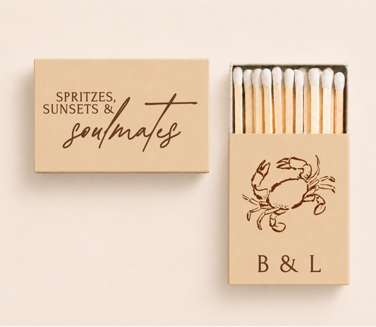 Personalized coastal wedding matchboxes featuring the phrase "Spritzes, Sunsets & Soulmates," custom initials, and a crab illustration for beach weddings.