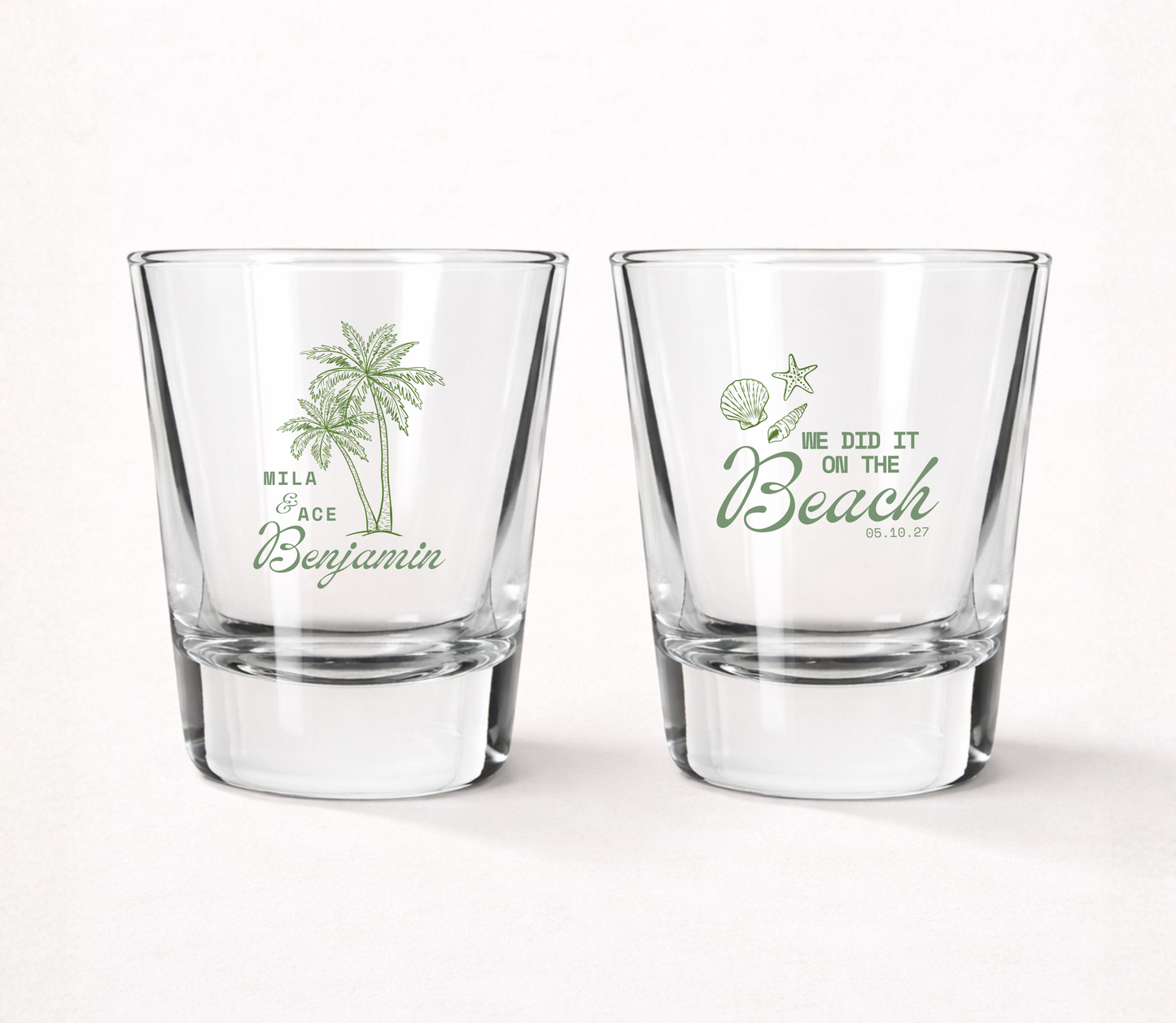 Clear personalized beach wedding shot glasses featuring tropical palm trees, custom couple names, beach themed artwork, and wedding date.