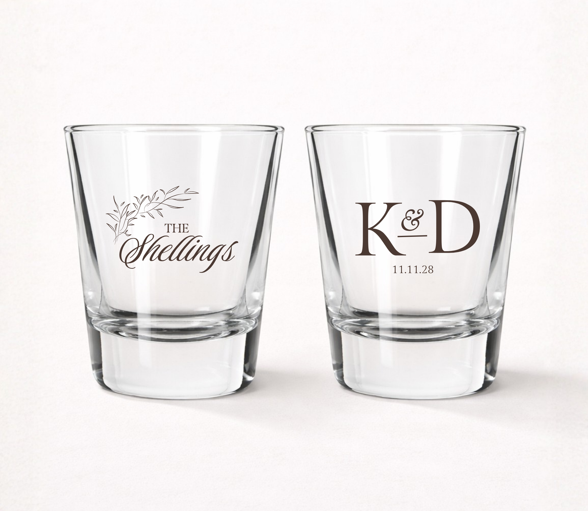 Personalized Shellings Monogram wedding shot glasses featuring custom family name, initials, wedding date, and elegant botanical accents.