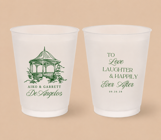 White frosted wedding cups featuring a custom gazebo venue illustration, couple names, family surname, romantic wedding quote, and wedding date.