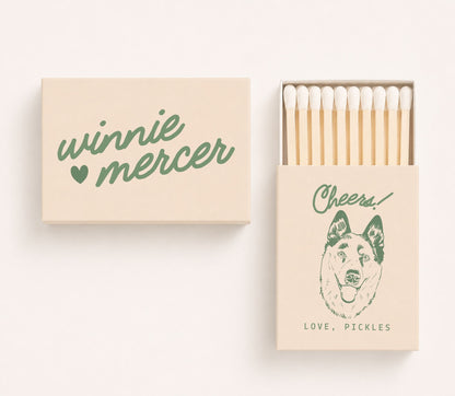 Personalized wedding matchboxes featuring custom couple names Winnie and Mercer on the cover and a dog portrait illustration with the phrase "Cheers! Love, Pickles" on the sliding matchbox.