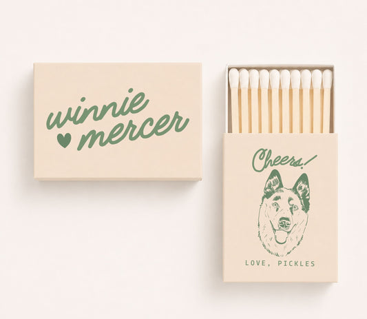 Personalized wedding matchboxes featuring custom couple names Winnie and Mercer on the cover and a dog portrait illustration with the phrase "Cheers! Love, Pickles" on the sliding matchbox.