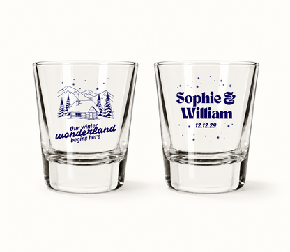 Personalized Winter Wonderland Christmas wedding shot glasses featuring snowy mountain cabin artwork, custom couple names, and wedding date.