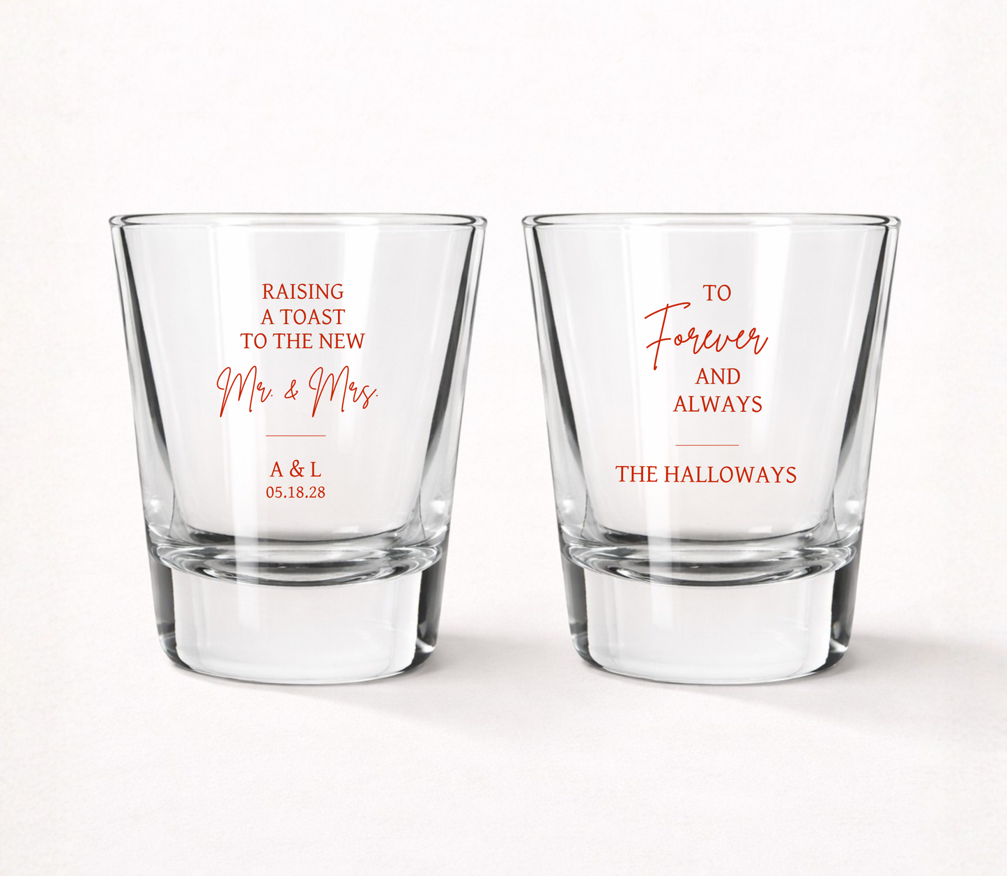 Personalized Raising A Toast wedding shot glasses featuring custom family name, couple initials, wedding date, and elegant Mr. & Mrs. wedding design.