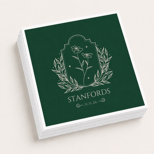 Dark green personalized wedding cocktail napkins featuring a wildflower botanical illustration, family surname Stanfords, and wedding date.
