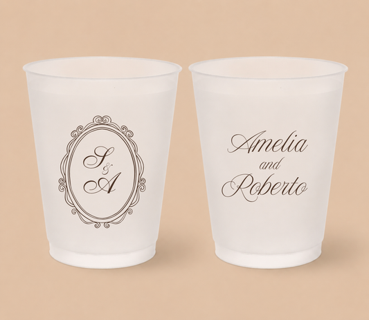 White frosted wedding cups featuring a vintage oval crest monogram with custom initials A and R and personalized couple names Amelia and Roberto.
