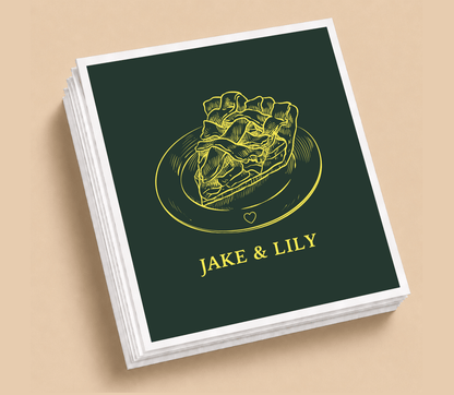 Personalized Thanksgiving wedding table napkins featuring a detailed pie illustration, custom couple names, and gold artwork on a forest green background.