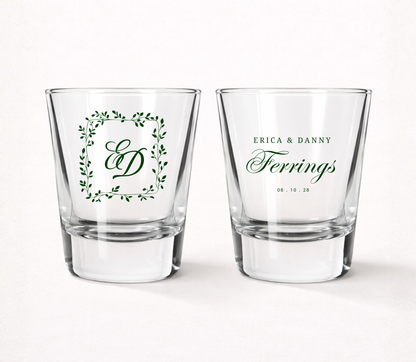 Personalized Ferrings Monogram wedding shot glasses featuring custom couple names, family name, monogram initials, wedding date, and botanical greenery frame.