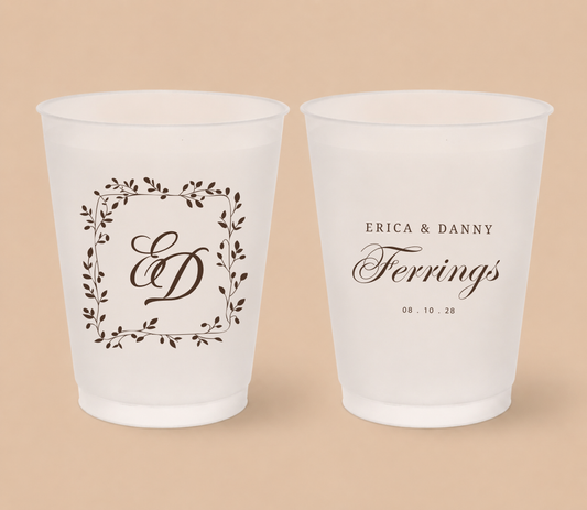 White frosted wedding cups featuring a botanical laurel monogram with initials ED, personalized names Erica and Danny Ferrings, and wedding date.