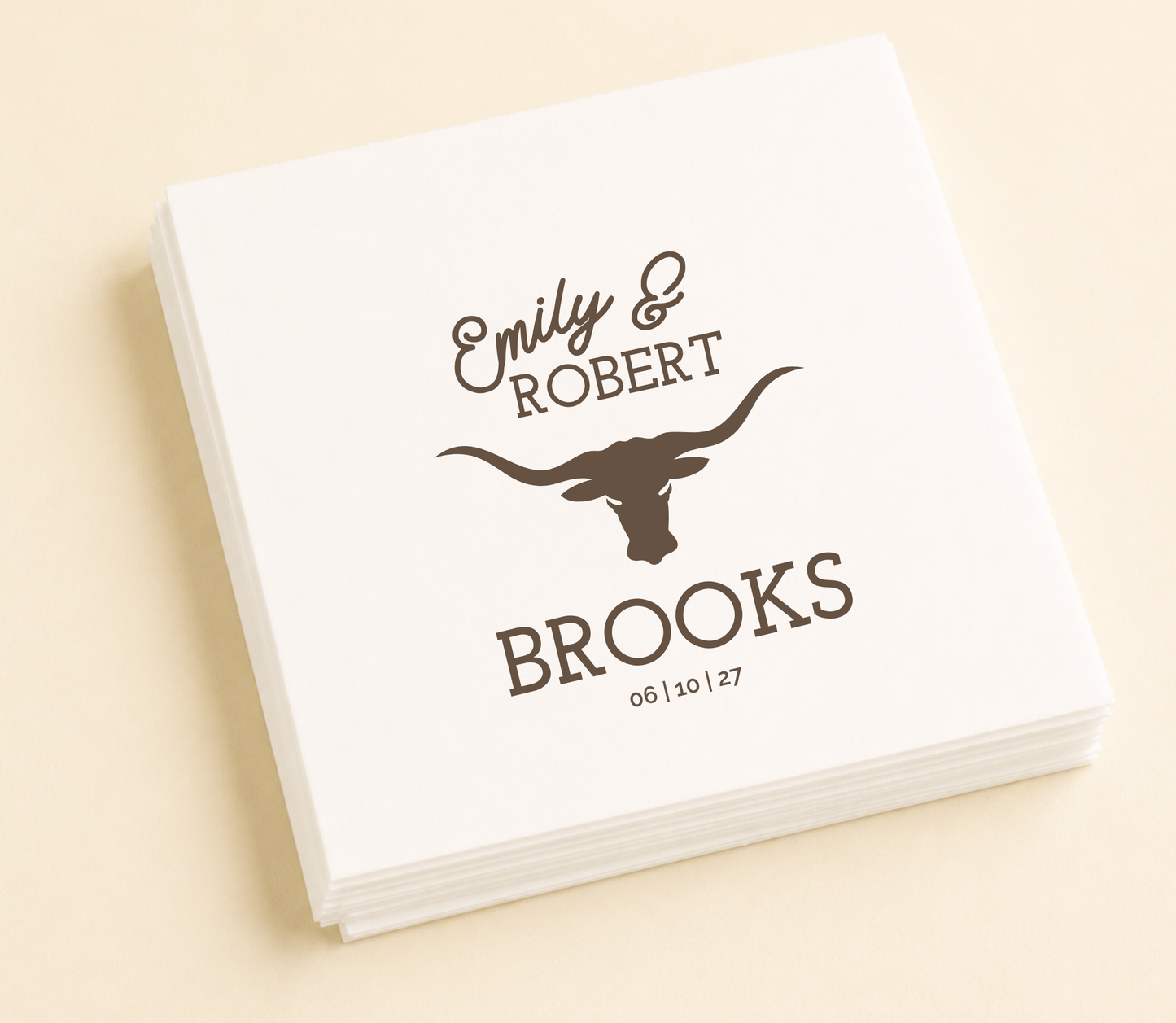 White personalized western wedding cocktail napkin featuring a longhorn silhouette, custom names Emily and Robert, family name Brooks, and wedding date.