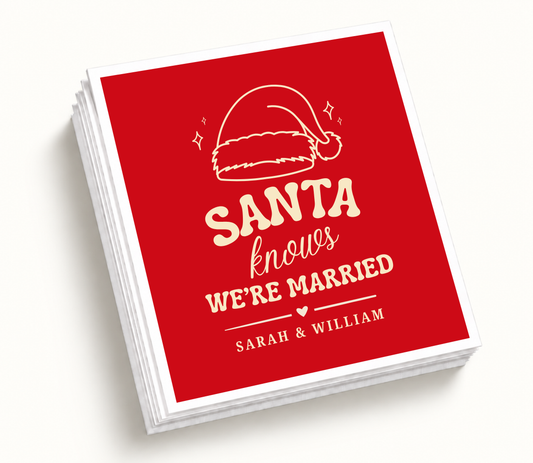 Personalized Santa Knows We're Married Christmas wedding napkins featuring red holiday background, ivory Santa hat artwork, custom couple names, and wedding details.