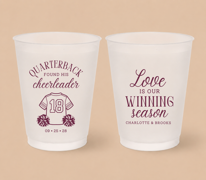 Personalized quarterback cheerleader football wedding cups featuring a football jersey, pom-poms, custom couple names, and Love Is Our Winning Season design.