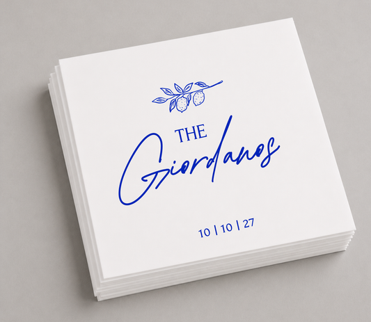 White personalized cocktail napkins featuring a blue lemon branch illustration, custom Giordano family name, and wedding date October 10, 2027.