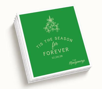 Personalized Tis The Season For Forever Christmas wedding napkins featuring green background, ivory mistletoe artwork, custom couple names, and holiday wedding design.