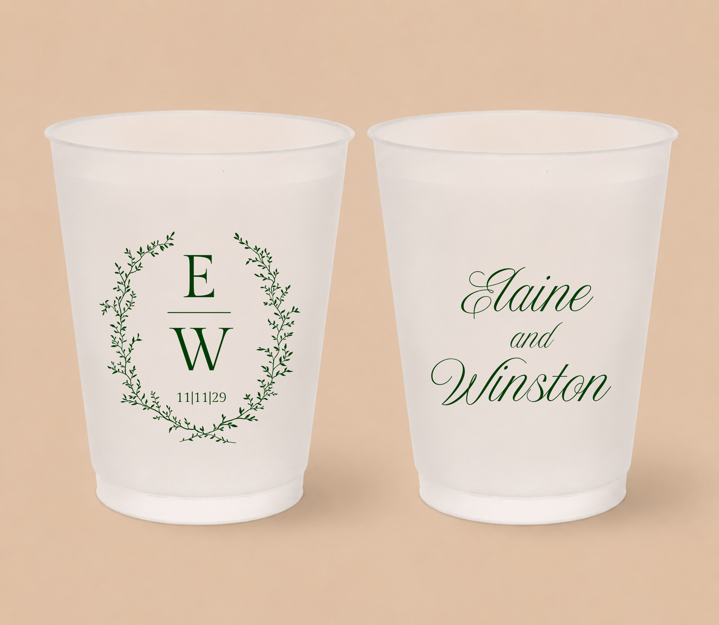 White frosted wedding cups featuring a botanical greenery wreath with custom initials E and W, wedding date, and personalized names Elaine and Winston.