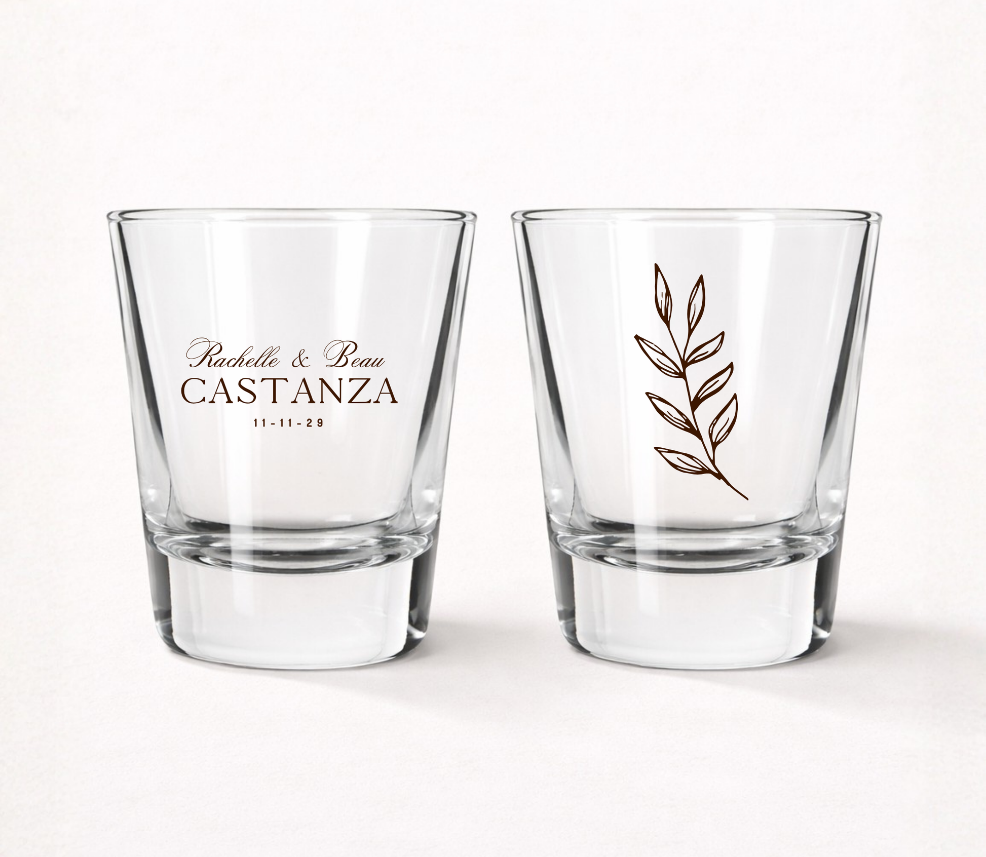 Clear personalized botanical wedding shot glasses featuring custom couple names, wedding date, and minimalist botanical leaf illustration.