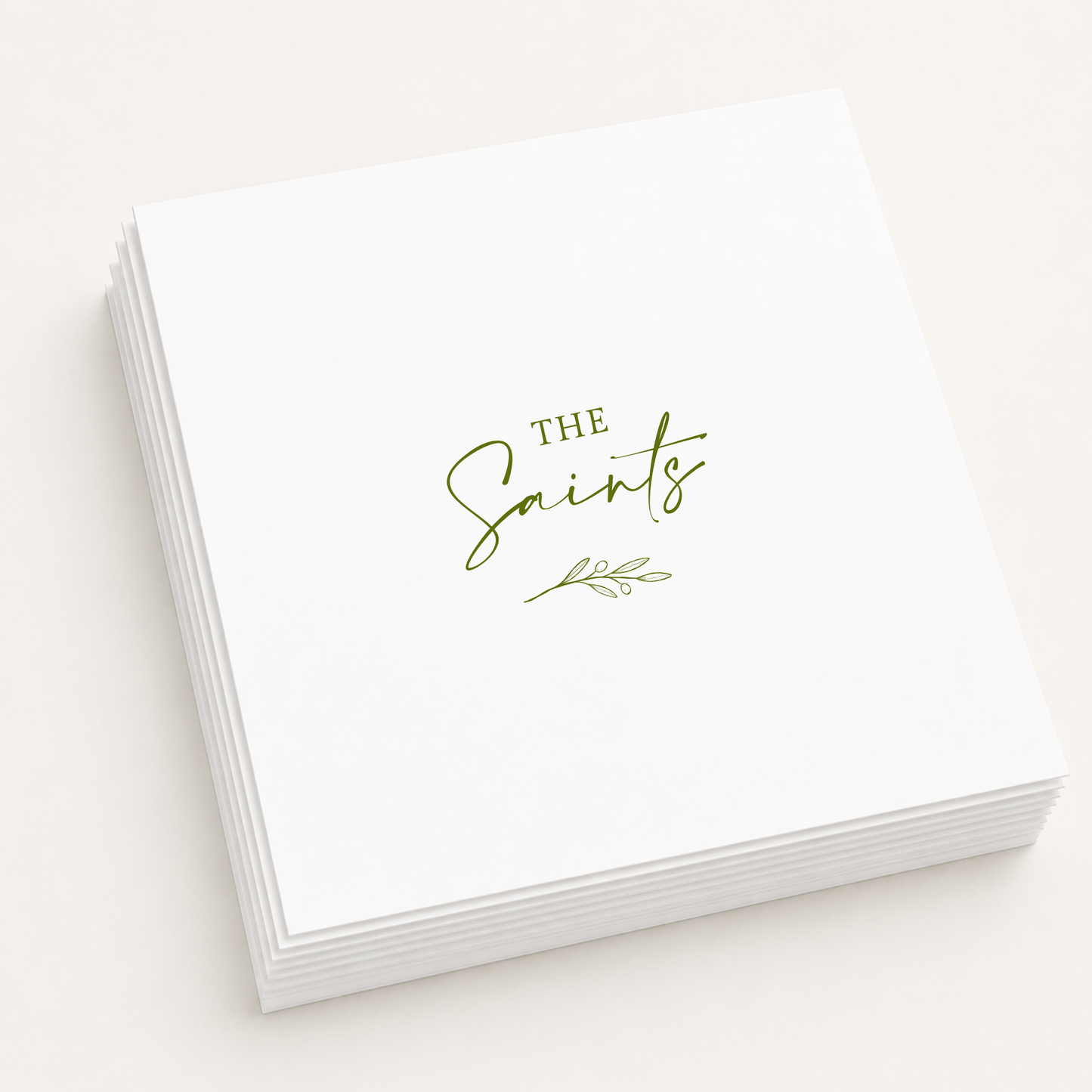 White personalized wedding cocktail napkins featuring custom family name "The Saints" with an elegant olive branch illustration in olive green ink.
