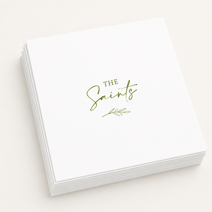 White personalized wedding cocktail napkins featuring custom family name "The Saints" with an elegant olive branch illustration in olive green ink.
