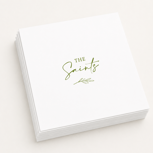 White personalized wedding cocktail napkins featuring custom family name "The Saints" with an elegant olive branch illustration in olive green ink.
