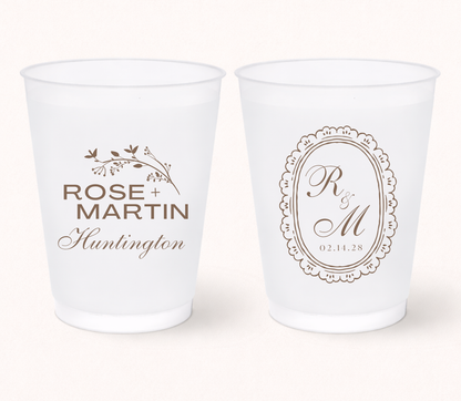 Two white frosted cups with personalized designs on a white background
