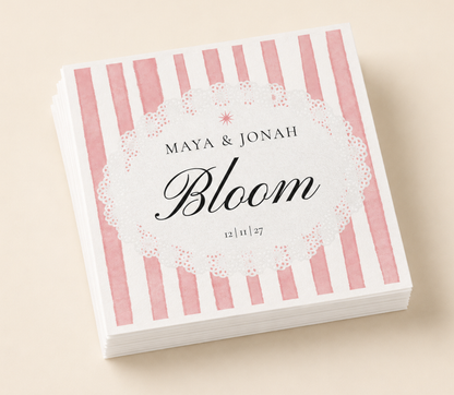 Personalized Bloom wedding napkins with pink striped design, custom names, wedding date, and black script typography on white paper napkins