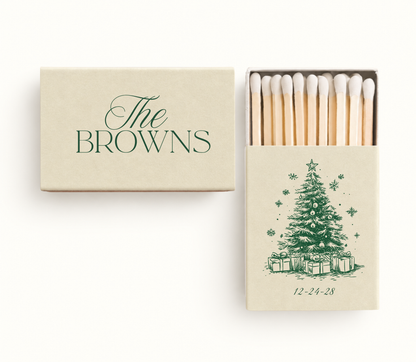 Personalized Christmas wedding matchboxes featuring a cream cover, custom family name, green Christmas tree illustration, and wedding date.