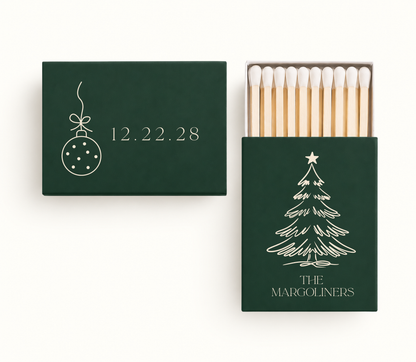 Personalized Christmas wedding matchboxes featuring deep green covers, cream Christmas tree and ornament artwork, custom family name, and wedding date.