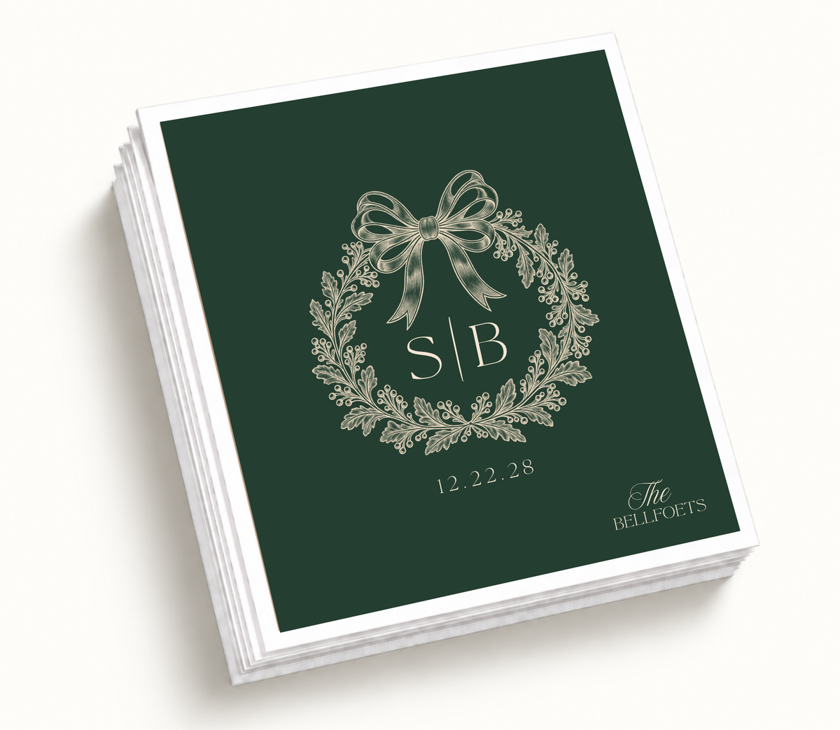 Personalized Christmas wedding napkins featuring a deep green holiday wreath, cream bow, custom initials, family name, and wedding date.